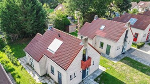 Une rangée de maisons à deux étages, avec des toits recouverts de tuiles rouges, des façades en briques et de petits balcons.
