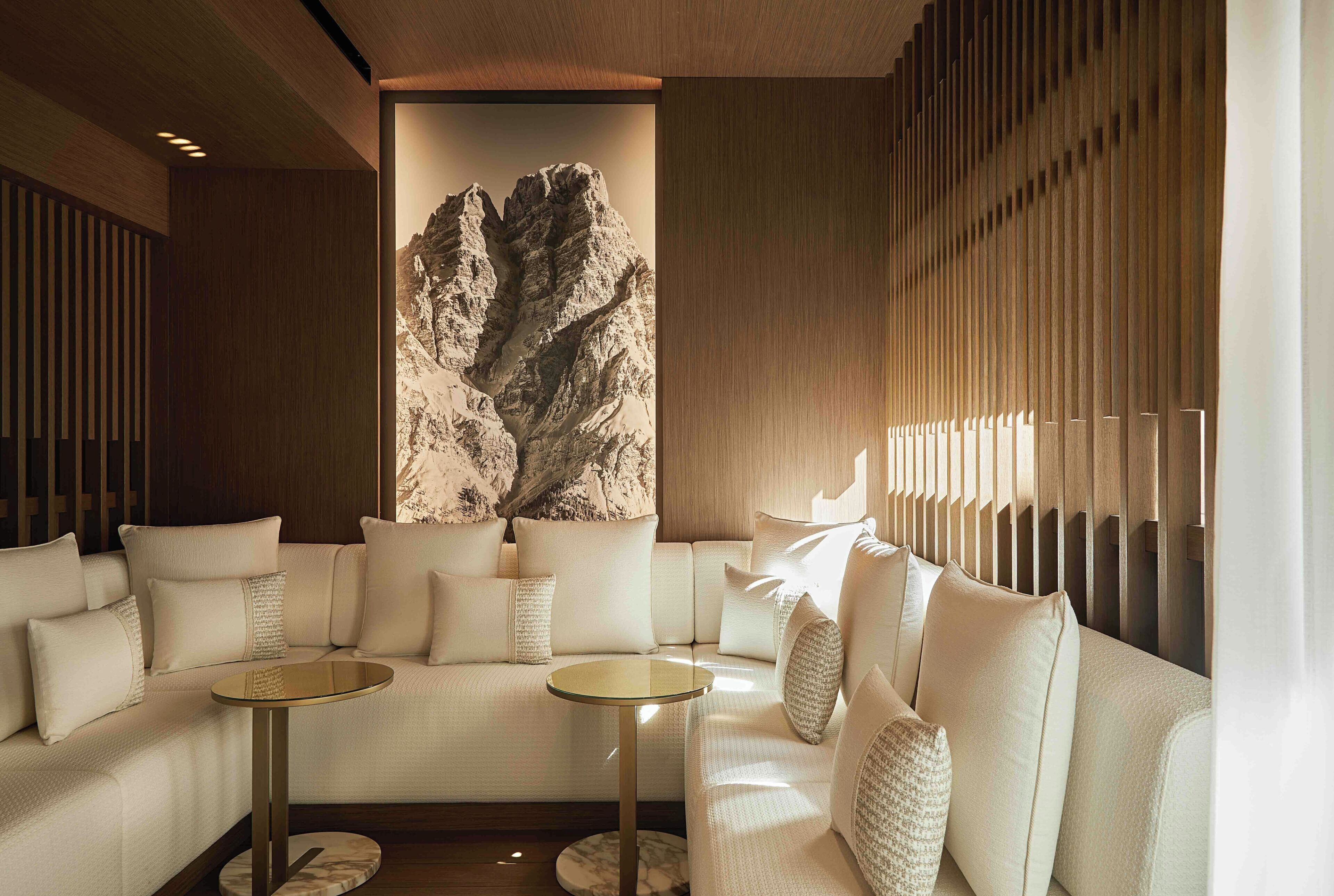 A modern interior with a sofa set, two small tables, and a large wall-mounted artwork of a mountainous landscape.