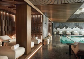 A modern spa area with wooden paneling, a pool with a mountain mural, and multiple seating areas. - Grand Hotel Ampezzo (Cortina d'Ampezzo)