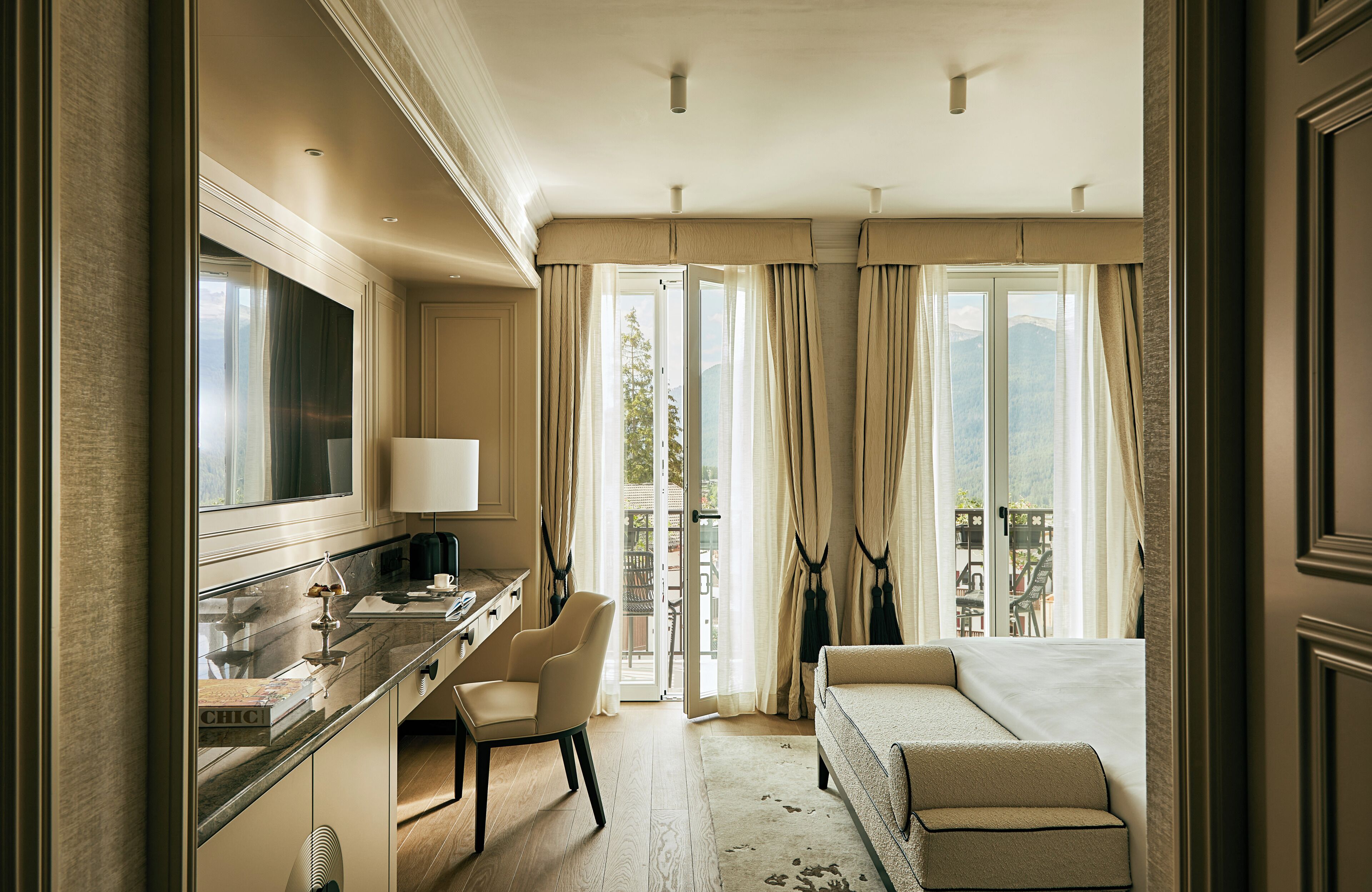 Ein Hotelzimmer mit Schreibtisch, Stuhl, Sofa und Blick ins Freie.