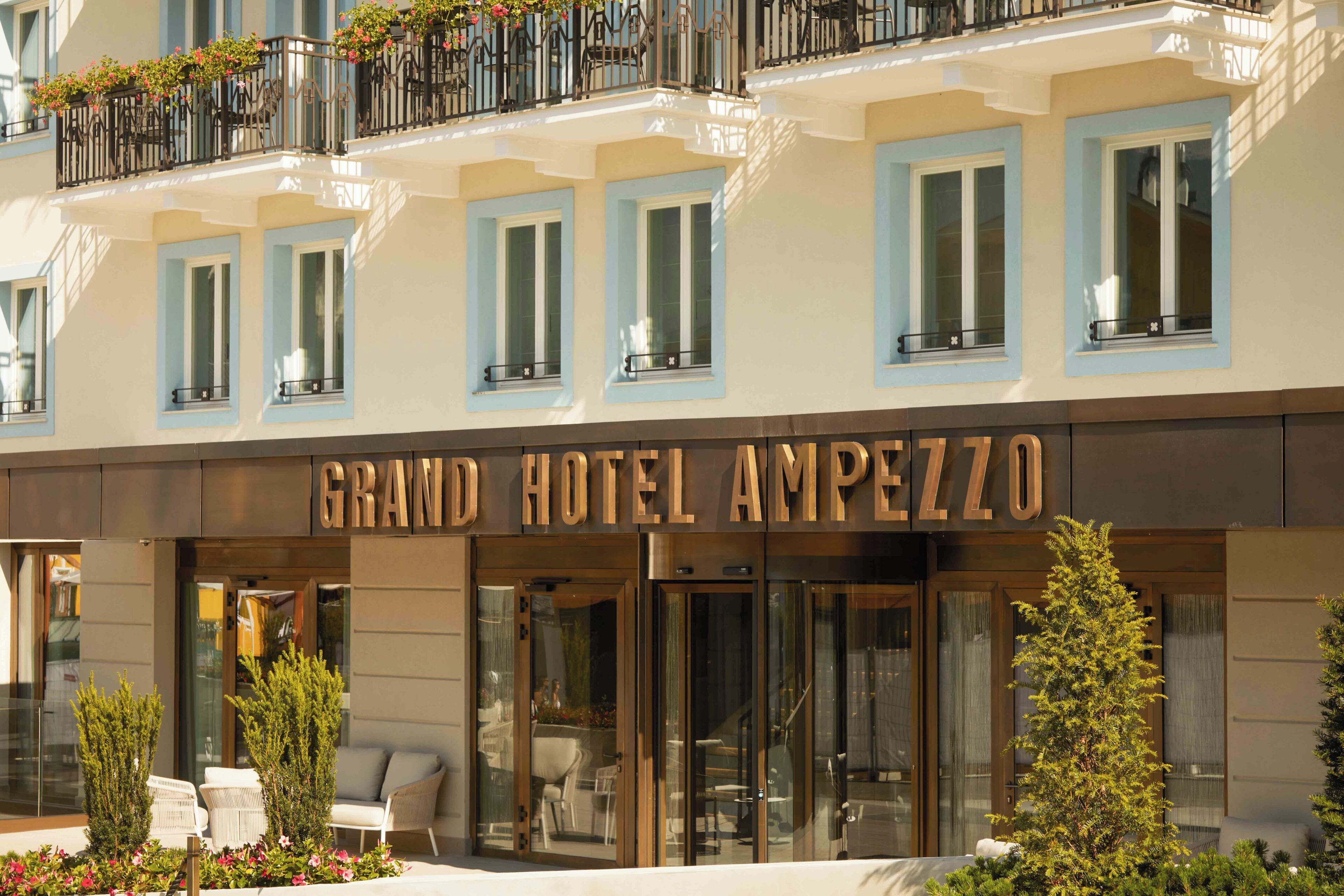 A hotel facade with multiple windows, a prominent entrance, and outdoor seating.