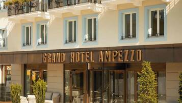 A hotel facade with multiple windows, a prominent entrance, and outdoor seating.
