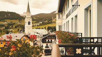 Un balcón con vistas a un pueblo, que incluye una torre de iglesia y edificios residenciales.