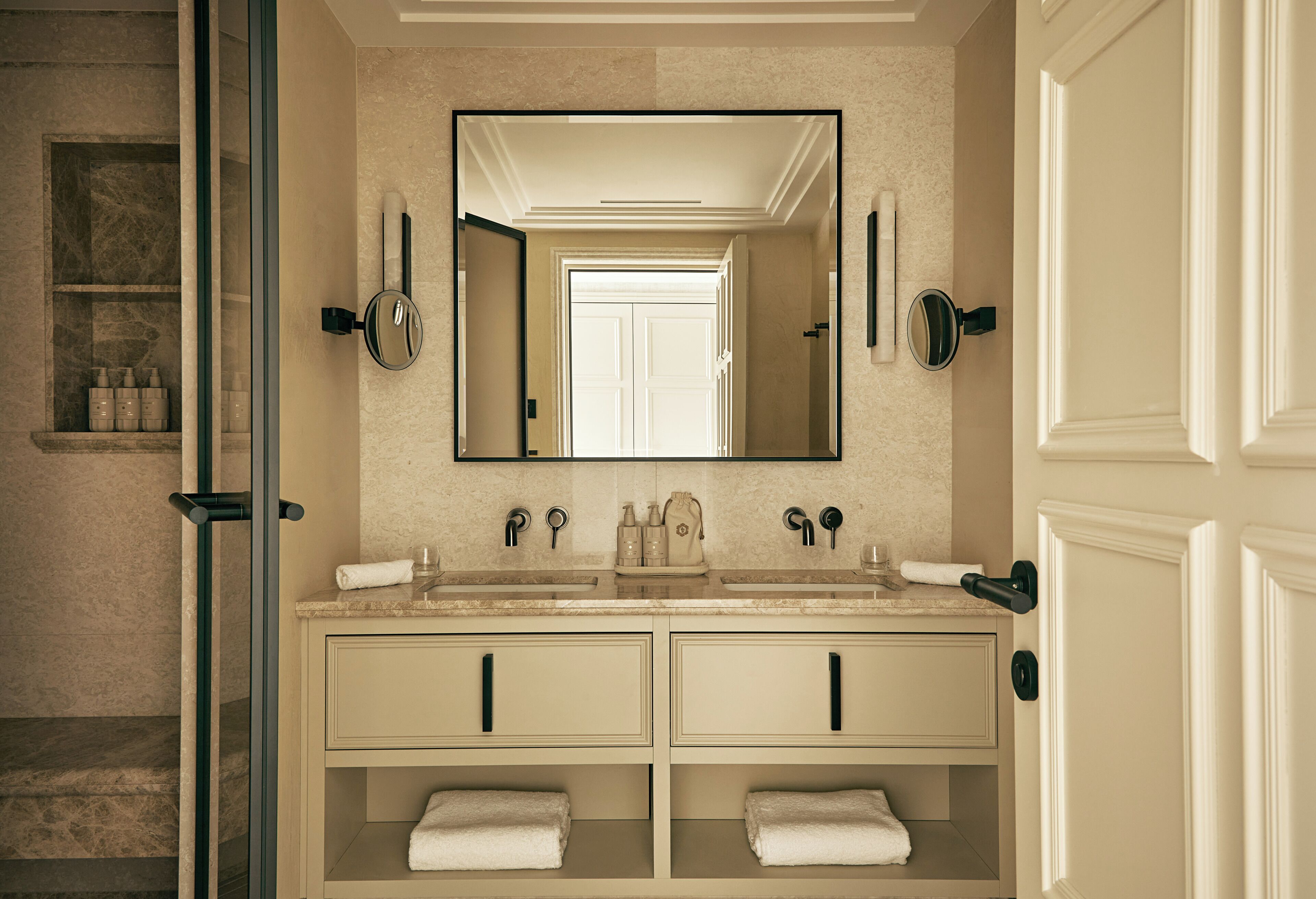 A bathroom with a double sink, a large mirror, and a glass shower enclosure.