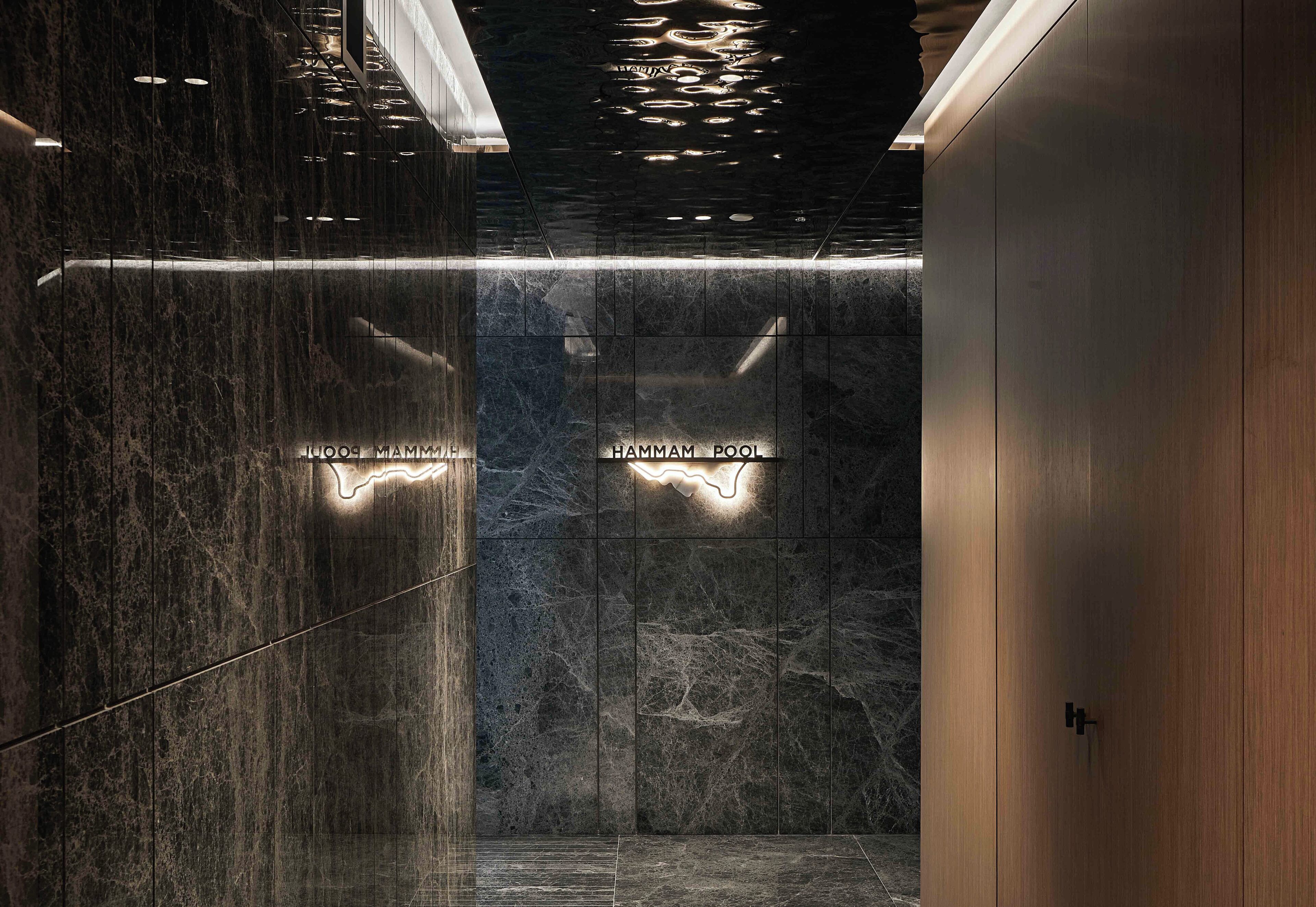 A modern elevator interior with marble walls and illuminated signage.