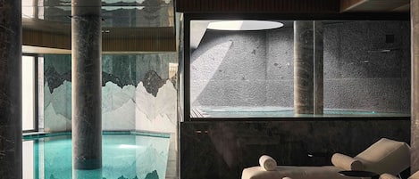 Un área de spa con piscina, asientos y un amplio ventanal con pared texturizada.