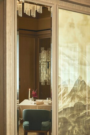 A dining area with a table set for two, a candle, and a vase with flowers. - Grand Hotel Ampezzo (Cortina d'Ampezzo)