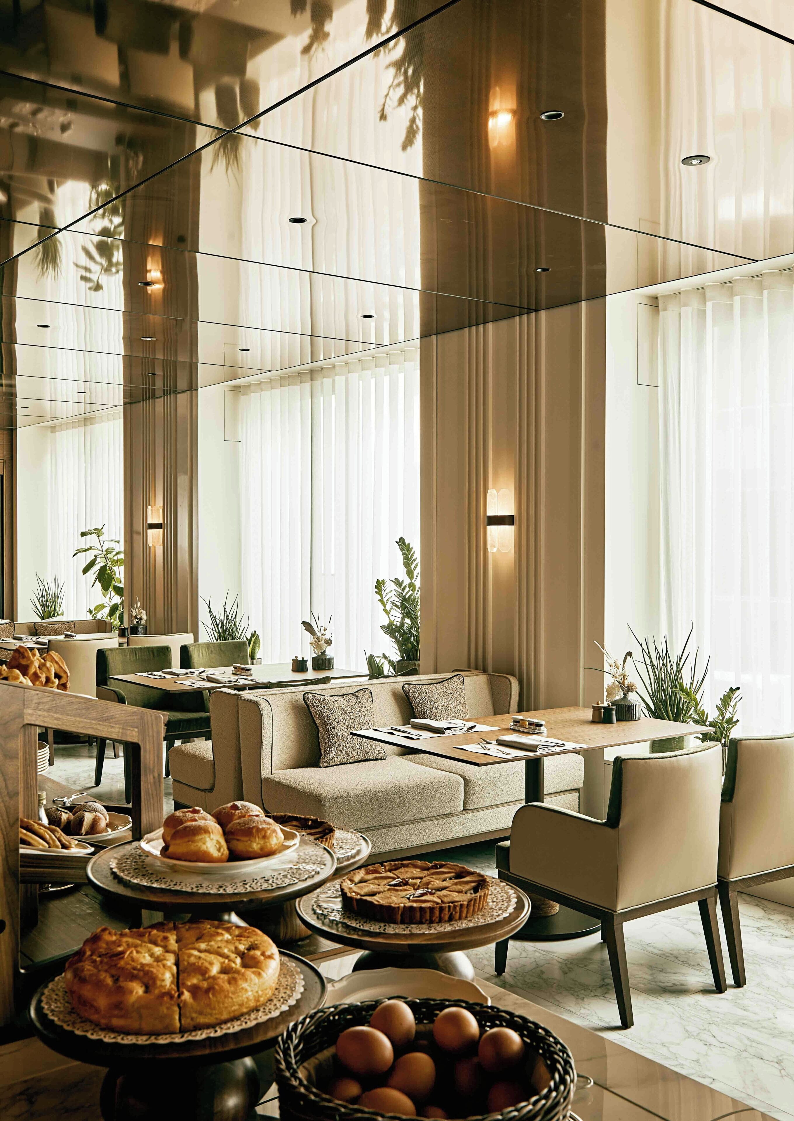 A modern interior with a seating area, dining tables, and a variety of baked goods.
