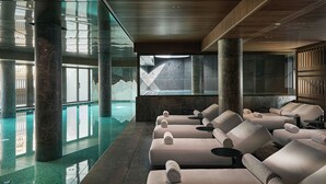 Un área de spa con piscina, sillas de masaje y una pared de piedra.