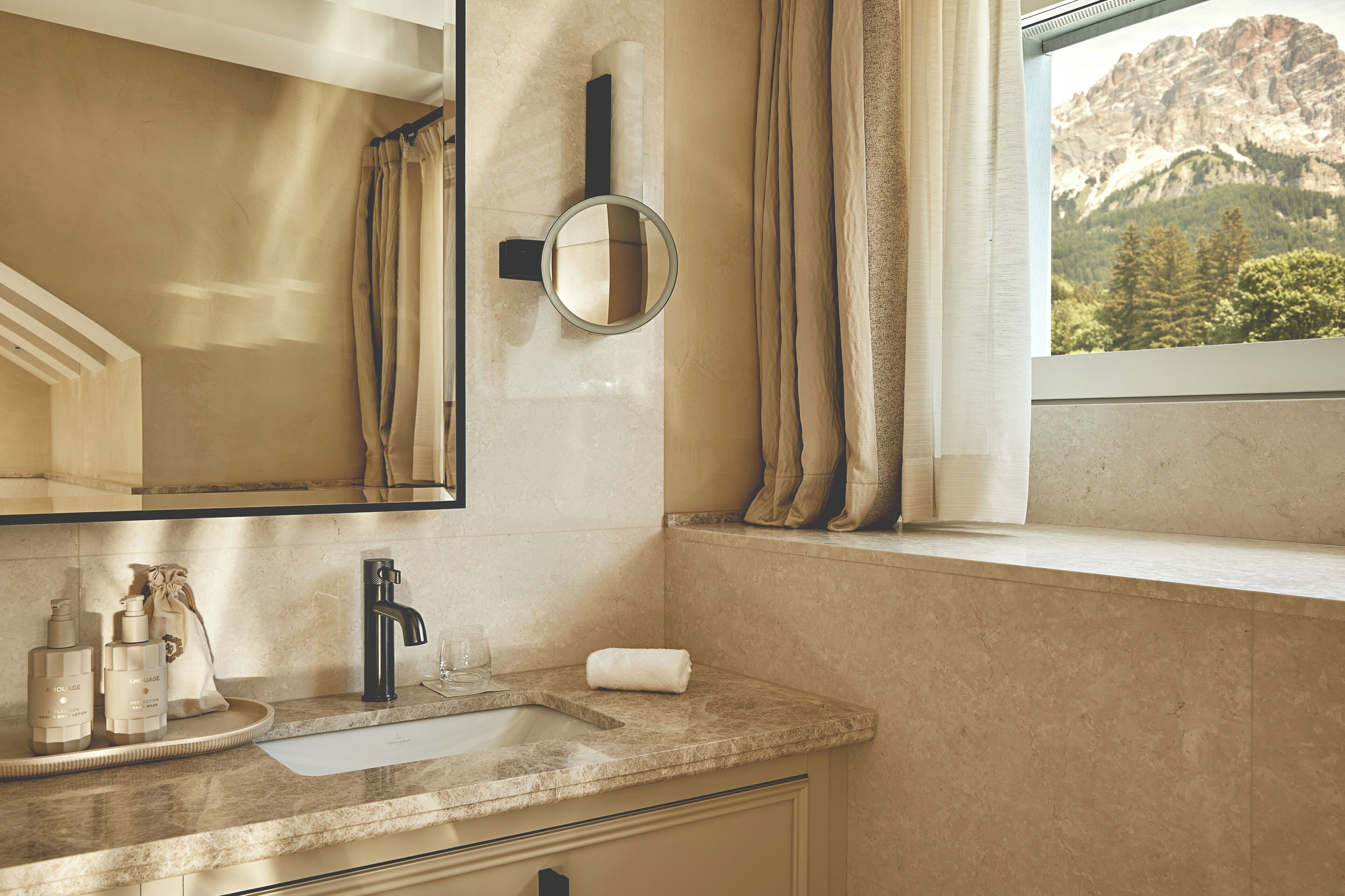 Un baño con lavamanos, espejo y ventana con vistas a la montaña.