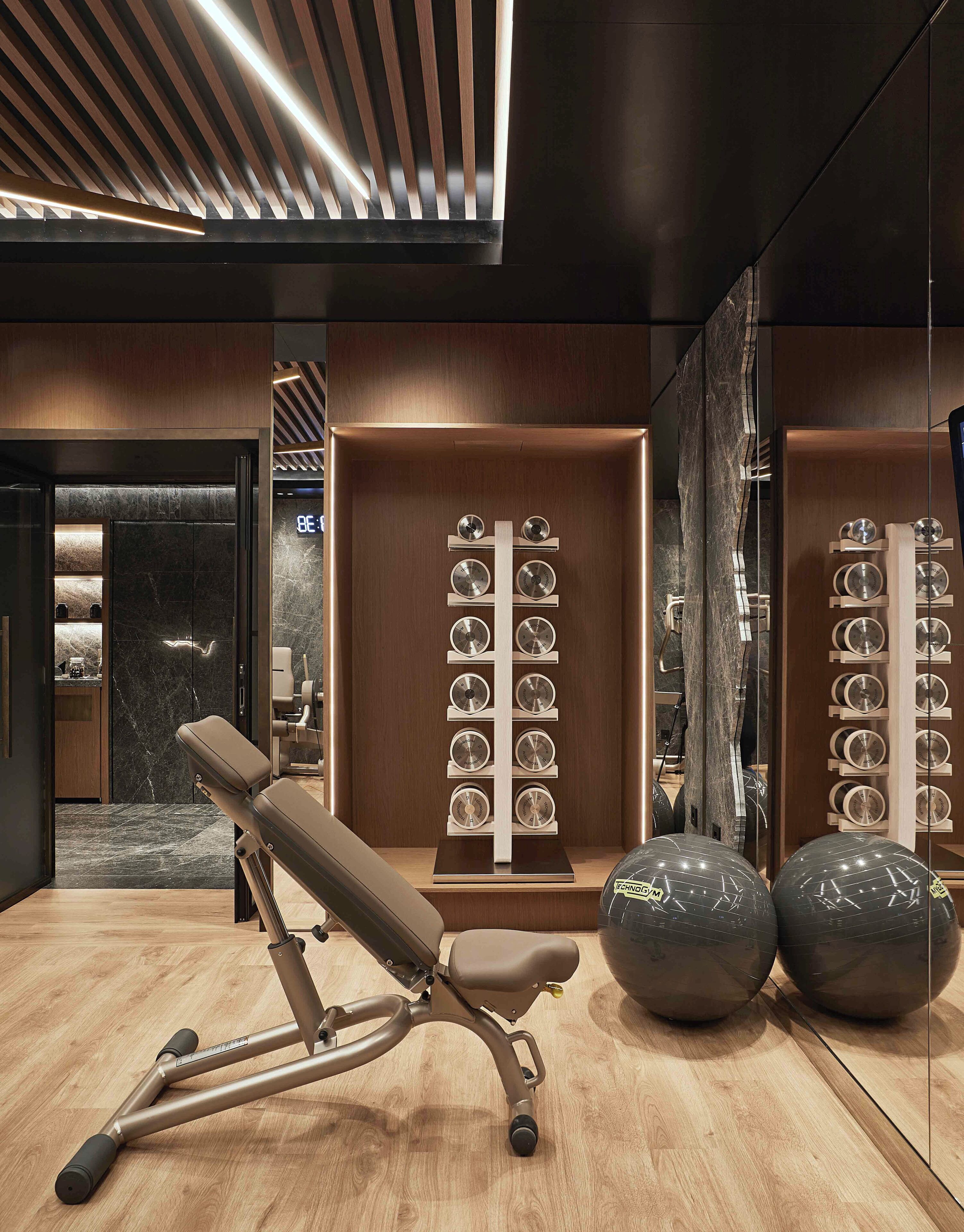 Et moderne fitnesscenter med træningsudstyr, en marmorvæg og en spejlvæg.