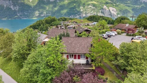 Una zona residencial con casas, un estacionamiento y un lago al fondo.