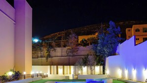 A nighttime view of a hotel courtyard with a swimming pool, a well-lit reception area, and a mountain backdrop. - Petra Castle Hotel (Wadi Musa)