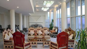A spacious hotel lobby with high ceilings, large windows, and a central seating area with ornate furniture. - Petra Castle Hotel (Wadi Musa)