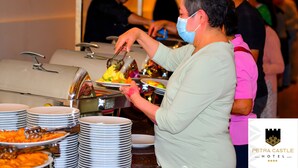 A buffet setup with multiple food stations and stacked plates. - Petra Castle Hotel (Wadi Musa)