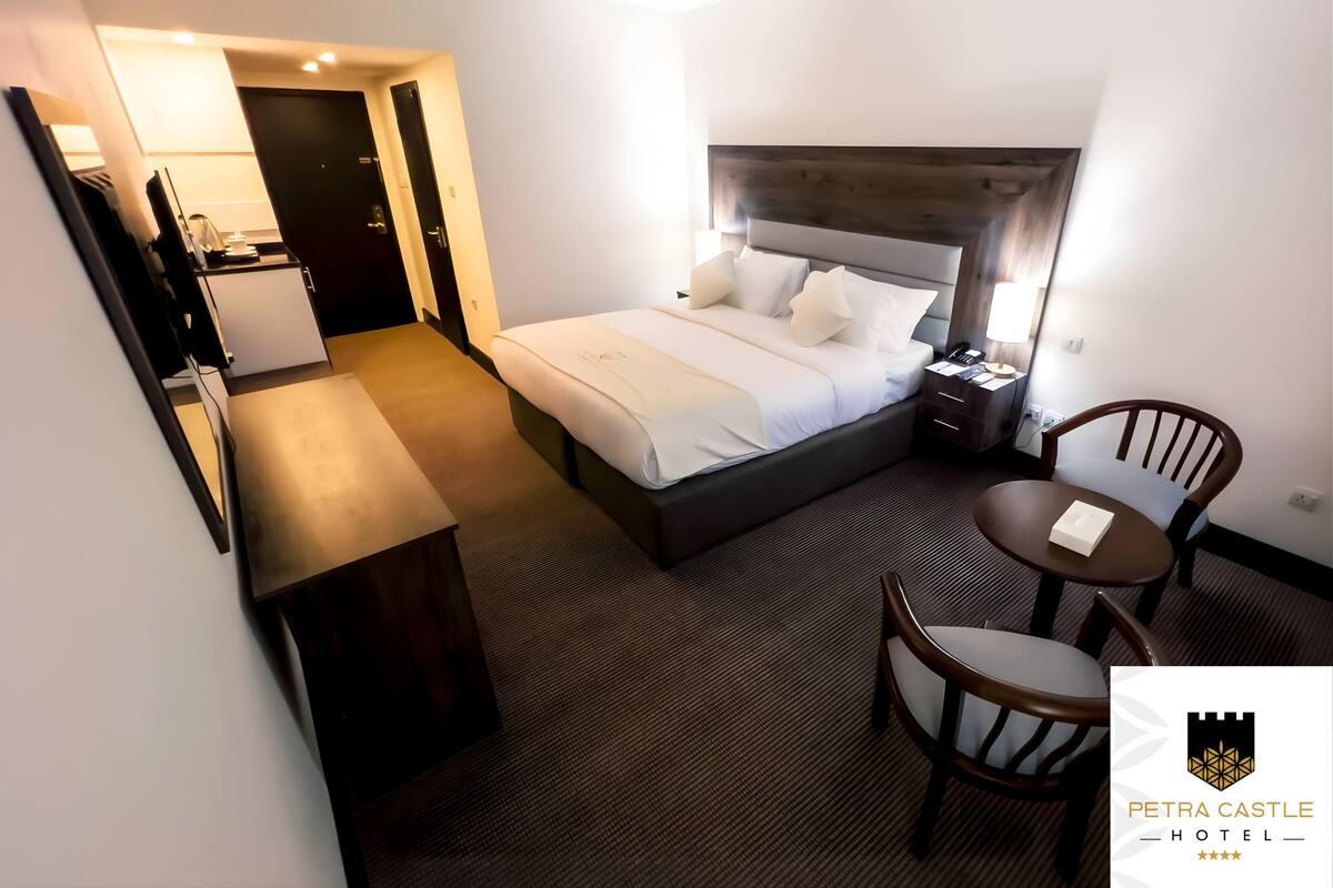 Une chambre d’hôtel comprenant un lit, une table de chevet, une chaise, un bureau et une lampe.