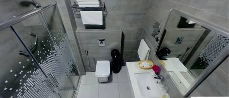 A modern bathroom with a glass shower enclosure, a white sink with a mirror, and a toilet.