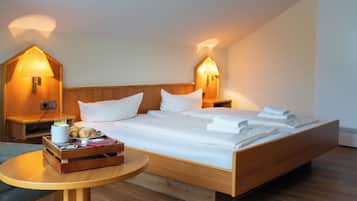 Een hotelkamer met een groot bed, twee bedlampen, een nachtkastje met een dienblad met ontbijtartikelen, en een klein rond tafeltje.