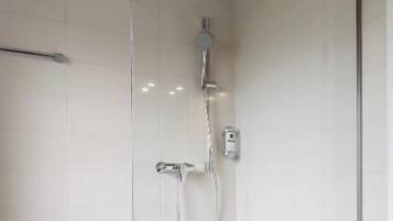 Eine moderne Duschkabine mit Glastür, Handbrause und am Wand befestigtem Wasserhahn.