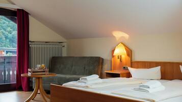 Habitación de hotel con una cama, una silla, una mesita con provisiones para el desayuno, una mesita de noche con una lámpara y vistas a zonas verdes.