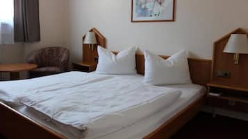 Une chambre d’hôtel avec un grand lit, deux tables de chevet avec des lampes, une chaise et un tableau au mur.