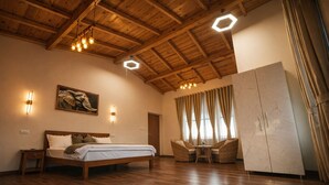 Une pièce avec un plafond en bois, un lit, deux chaises, une table et une armoire.