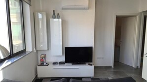 A modern living room with a flat-screen TV on a white entertainment unit, a gray sofa, and a large window. - Seaview 1-bedroom apartment with AC in St. Julian's (St. Julian's)