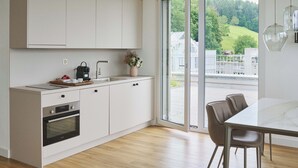 Una cocina moderna con horno integrado, cafetera y un florero con flores.