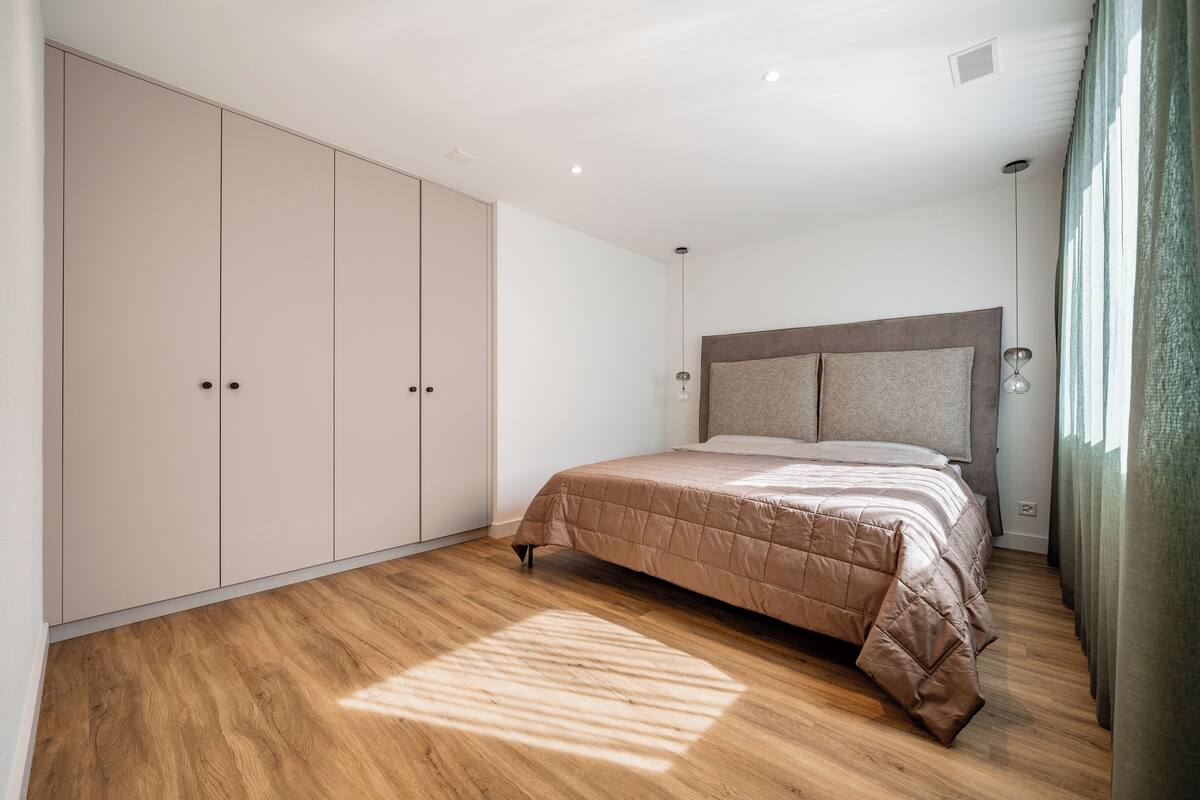Un dormitorio con cama, armario y cabecera.