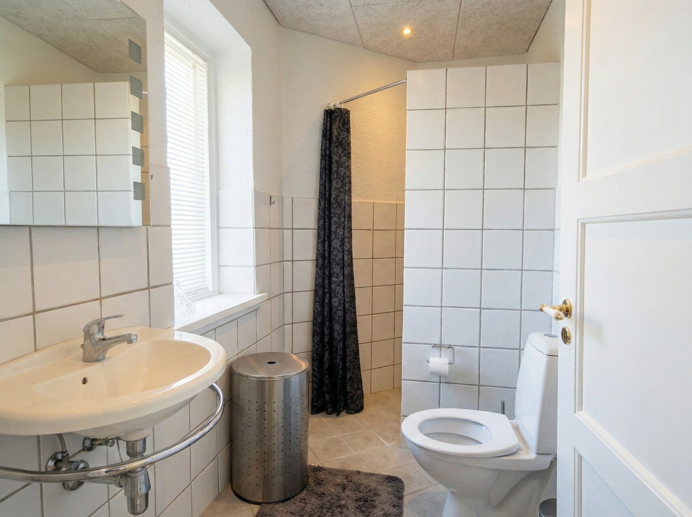 Une salle de bain avec un lavabo blanc, des toilettes et un rideau de douche.