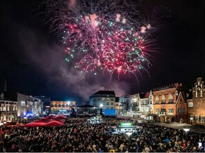Una plaza concurrida con edificios históricos y un escenario para un evento.
