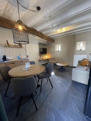 A modern kitchen with a herringbone tile backsplash, a wooden dining table, and a hanging light fixture. - 18. 4p Authentic Cosy Cottage (Voerendaal)