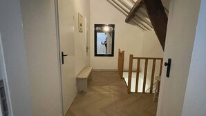 A narrow hallway with a wooden beam ceiling, a bench, and a door leading to another room. - 18. 4p Authentic Cosy Cottage (Voerendaal)