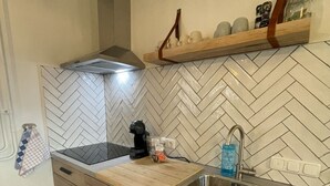 A compact kitchen with a herringbone tile backsplash, a wooden countertop, a stainless steel sink, and a built-in oven. - 18. 4p Authentic Cosy Cottage (Voerendaal)