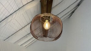 Ett sovrum med en stor säng, två sängbord med lampor och en unik, vävd taklampa.