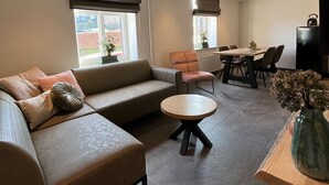 A modern living room with a sofa, a round coffee table, and a dining area with chairs and a table. - Valley View Cottage 07.  4p-Courtyard Cottage near Valkenburg (Voerendaal)