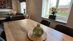 A dining area with a wooden table, woven placemat, and a green glass vase. - Valley View Cottage 07.  4p-Courtyard Cottage near Valkenburg (Voerendaal)