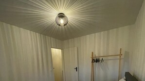 Una habitació d'hotel amb un llit gran, una tauleta de nit amb una làmpada i un armari amb mirall.