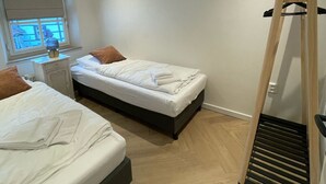 A bedroom with two beds, a wooden ladder, a window with blinds, and a bedside table with a lamp. - Spacious Holliday home in authentic farmhouse with terrace view (Voerendaal)