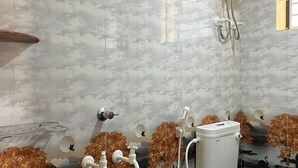 Kylpyhuone, jossa on marmoriseinä, wc, suihku ja vedenlämmitin.