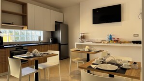 Une cuisine moderne avec un coin repas, équipée d’un réfrigérateur, d’une cuisinière et d’un téléviseur à écran plat.