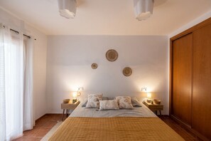 A bedroom with a bed, bedside tables, wall decor, and a wardrobe.