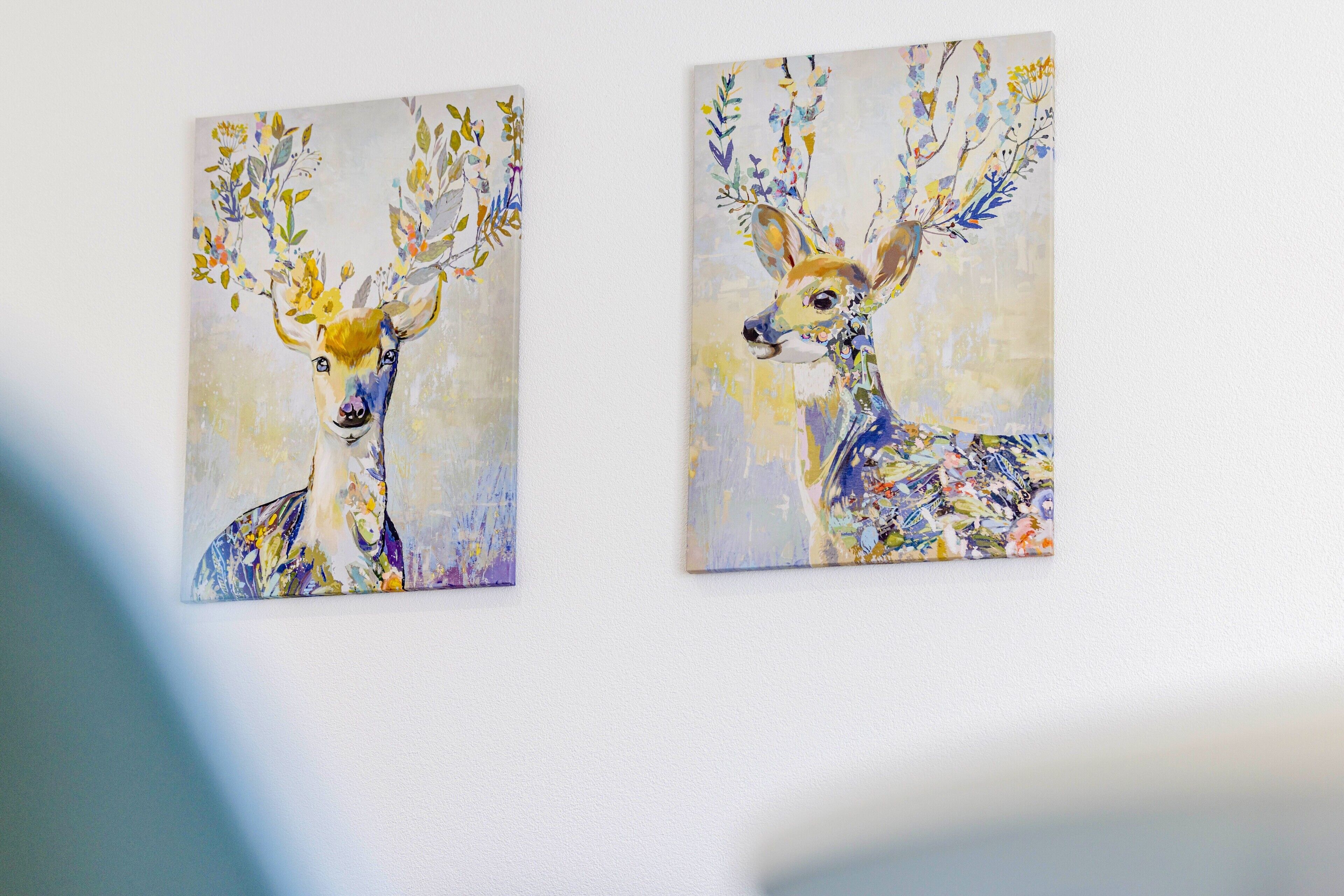 Deux tableaux représentant des cerfs, ornés de motifs floraux, et fixés au mur.