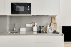 A modern kitchen with a Bosch microwave, stainless steel sink, and a wooden cutting board.