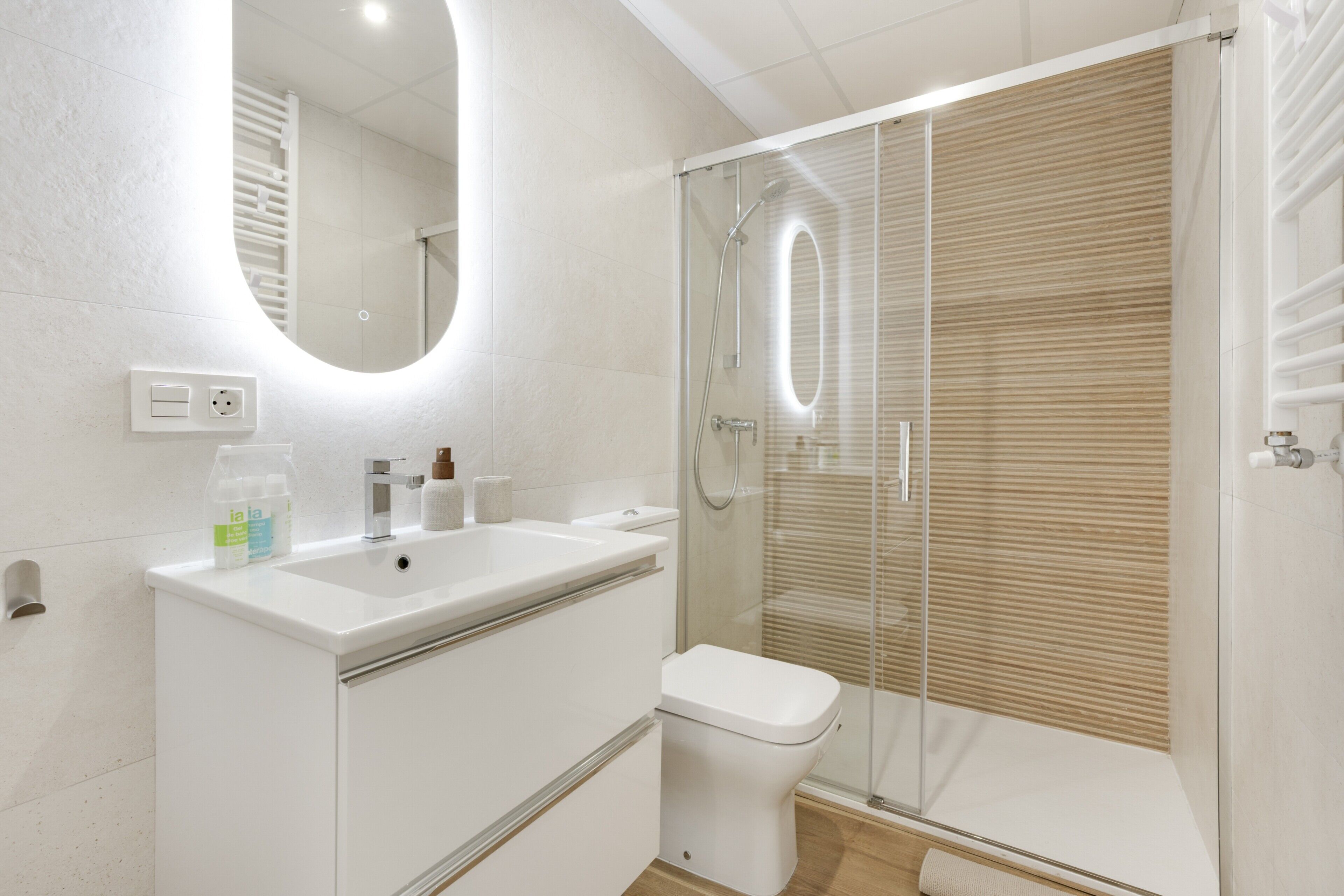 A modern bathroom with a glass-enclosed shower, a white sink, and a toilet.