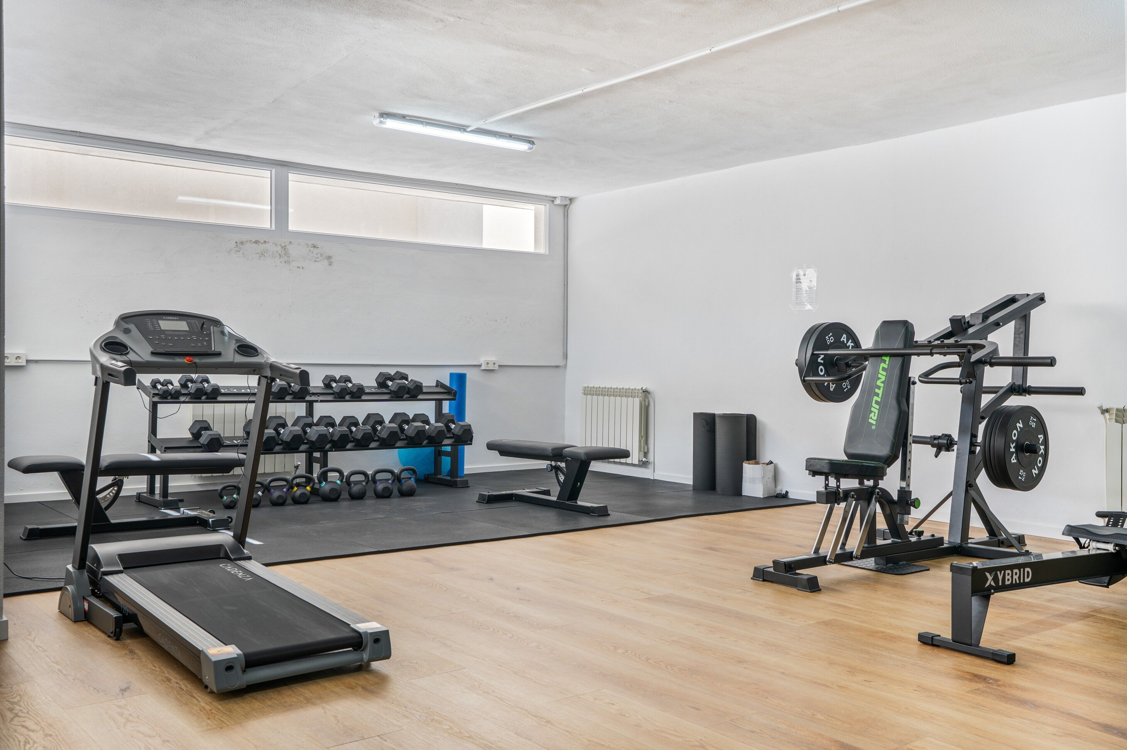 Ein Fitnessstudio mit Laufbändern, Hanteln und Krafttrainingsgeräten.