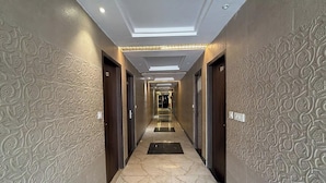 A hallway with patterned walls and a marble floor, leading to a door at the end. - Hotel Beubelle (Meerut)