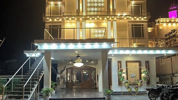 A hotel entrance with a grand staircase, a chandelier, and a decorative heart-shaped planter. - Hotel Beubelle (Meerut)