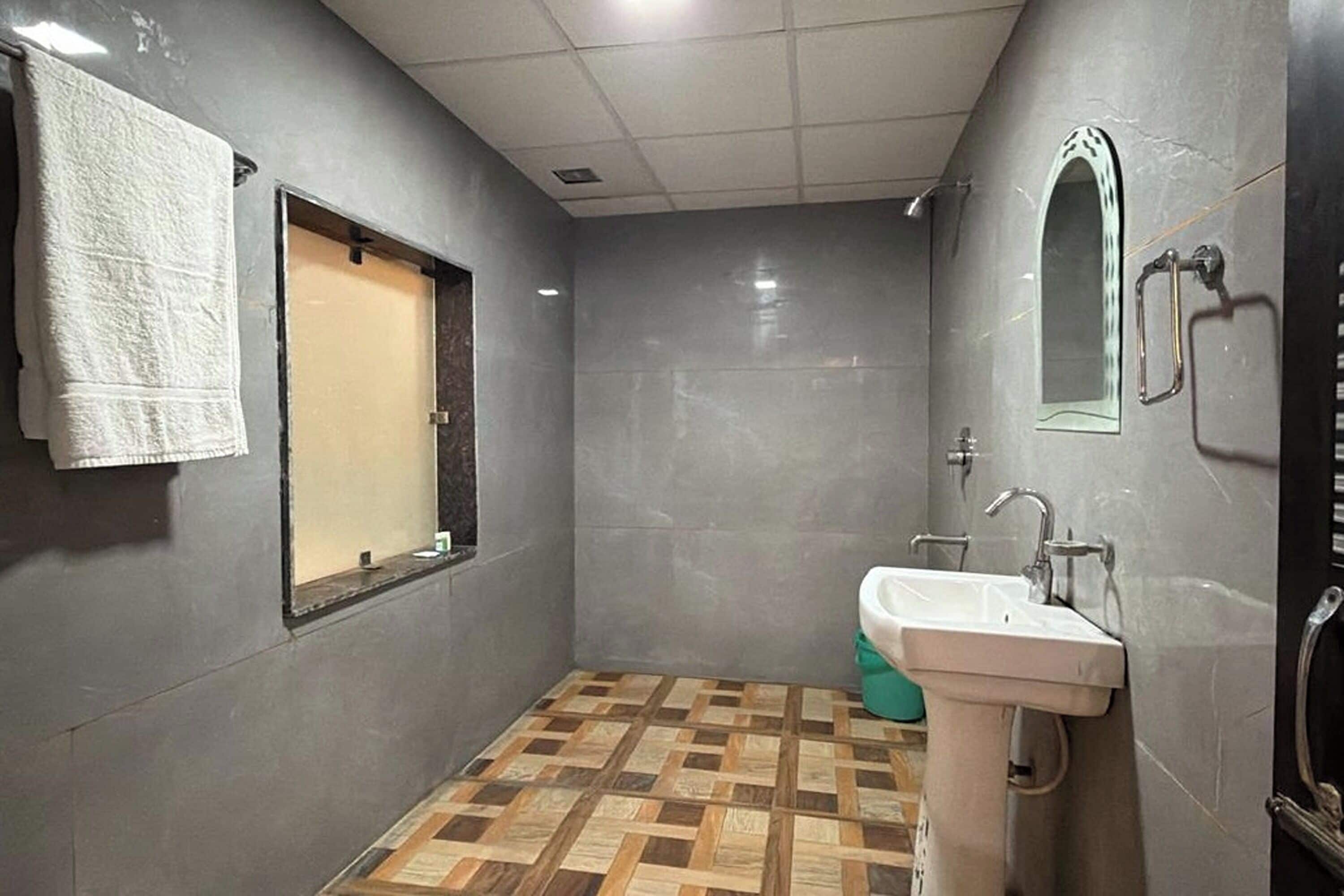 A bathroom with a tiled floor, a sink, a mirror, and a towel hanging on the wall.
