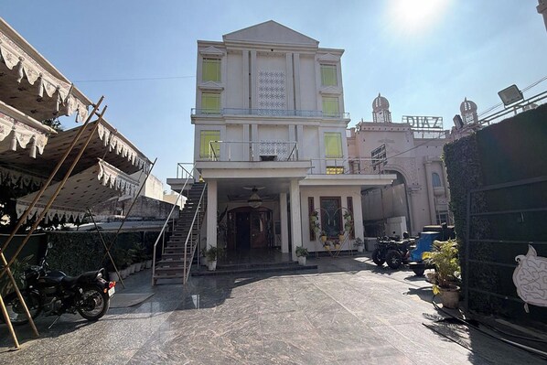 A two-story building with a central entrance, a balcony on the upper floor, and a staircase leading to the entrance.